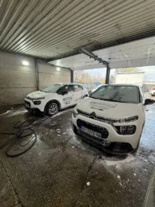 dva bela kompanijska automobila u procesu pranja marke dacia