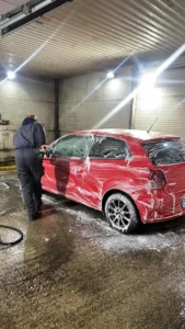 radnik u auto perionici četka crveni auto